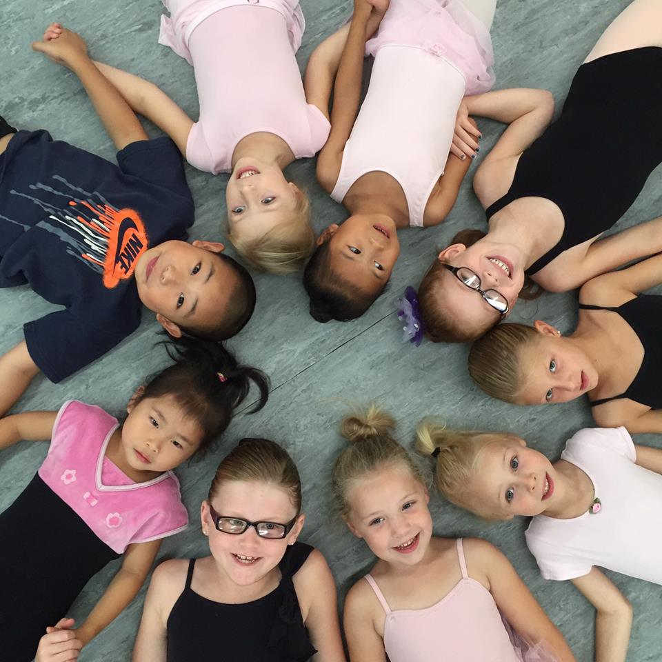 DSDW Dance students laying in a circle on the floor smiling